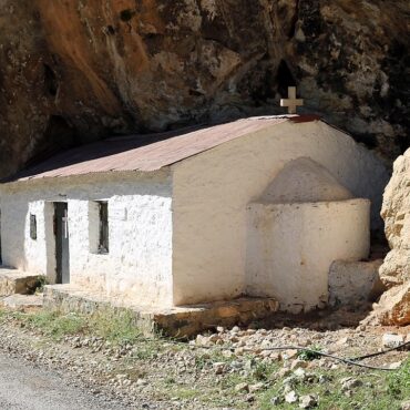 Ασβεστωμένο εκκλησάκι χτισμένο κάτω από βράχο δίπλα στον δρόμο έξω από τη Νέδουσα